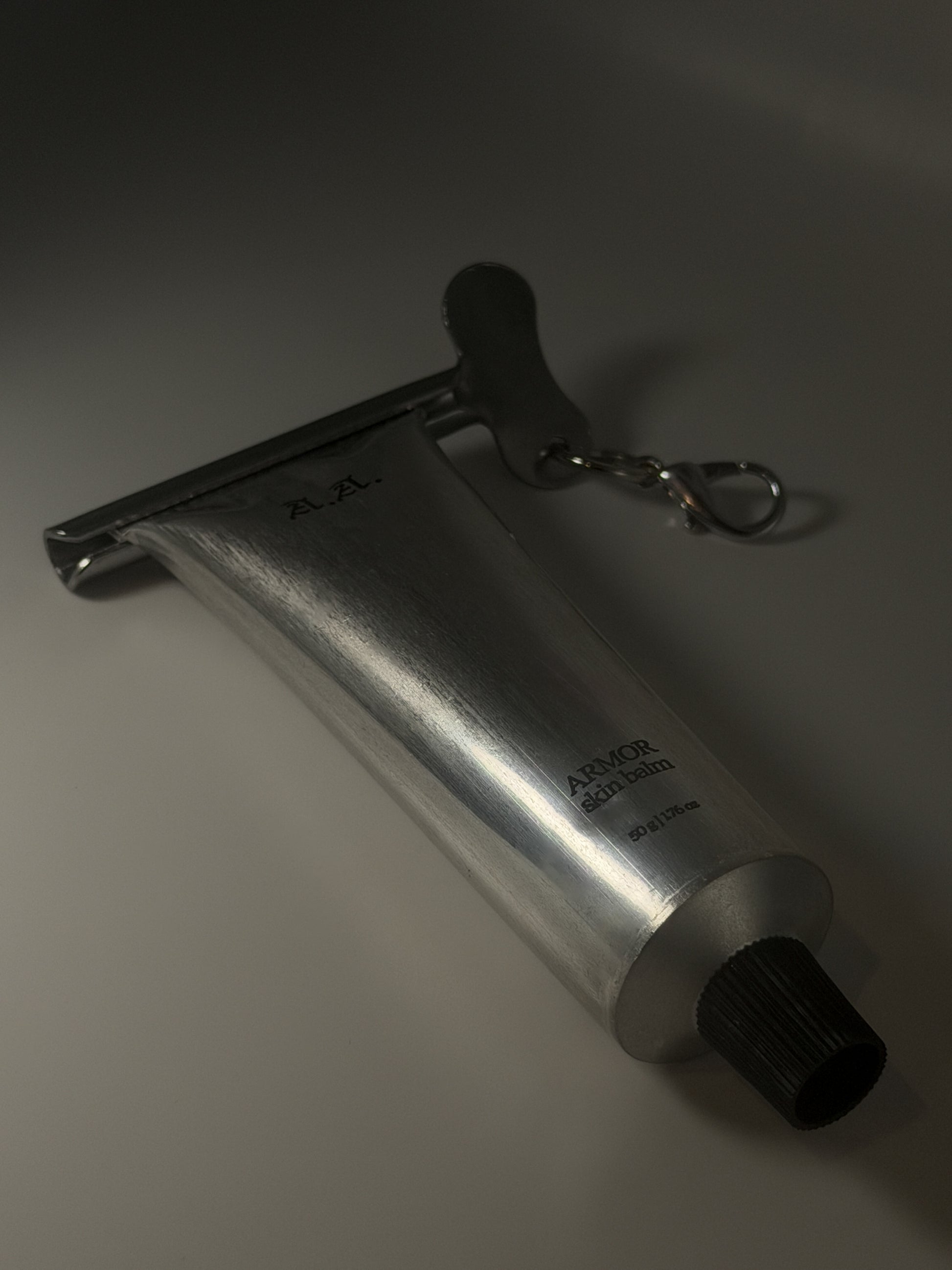 Metallic tool with a keychain on a gray background