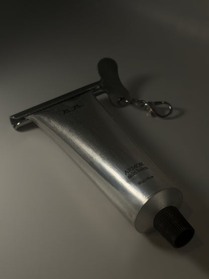 Metallic tool with a keychain on a gray background